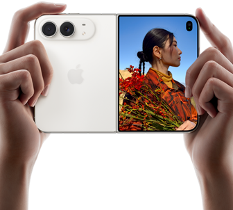 جهاز iPhone Duo، لون أبيض النجوم، يدان تحملان الجهاز في الوضع الأفقي، مفتوح، اللوحة اليسرى تعرض نظام كاميرا مزدوجة 48MP&nbsp;Fusion، اللوحة اليمنى تعرض شخصاً تُلتقط صورته على الشاشة الخارجية، يمكن لهذا الشخص رؤية وجهه لأن الصورة تُلتقط باستخدام ميزة Duo&nbsp;Preview‏