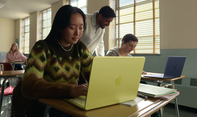 طالبة تستخدم جهاز MacBook Neo بلون أصفر سيتروس، غير موصول بالطاقة داخل قاعة دراسية