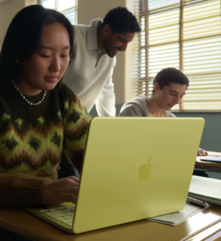 طالبة تستخدم جهاز MacBook Neo بلون أصفر سيتروس، غير موصول بالطاقة داخل قاعة دراسية