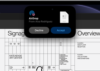شاشة تعرض Dynamic Island مع طلب إرسال سريع يظهر في نافذة صغيرة فوق ملف Adobe Acrobat مفتوح loading=